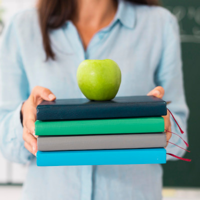 jabłko na książkach trzymanych przez osobę